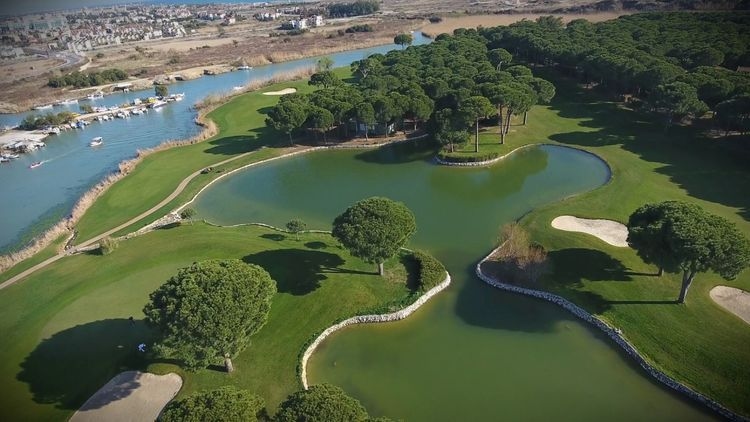 View over Nobilis Golf Course with manicured fairway, surrounding trees, and distant mountains under a clear sky