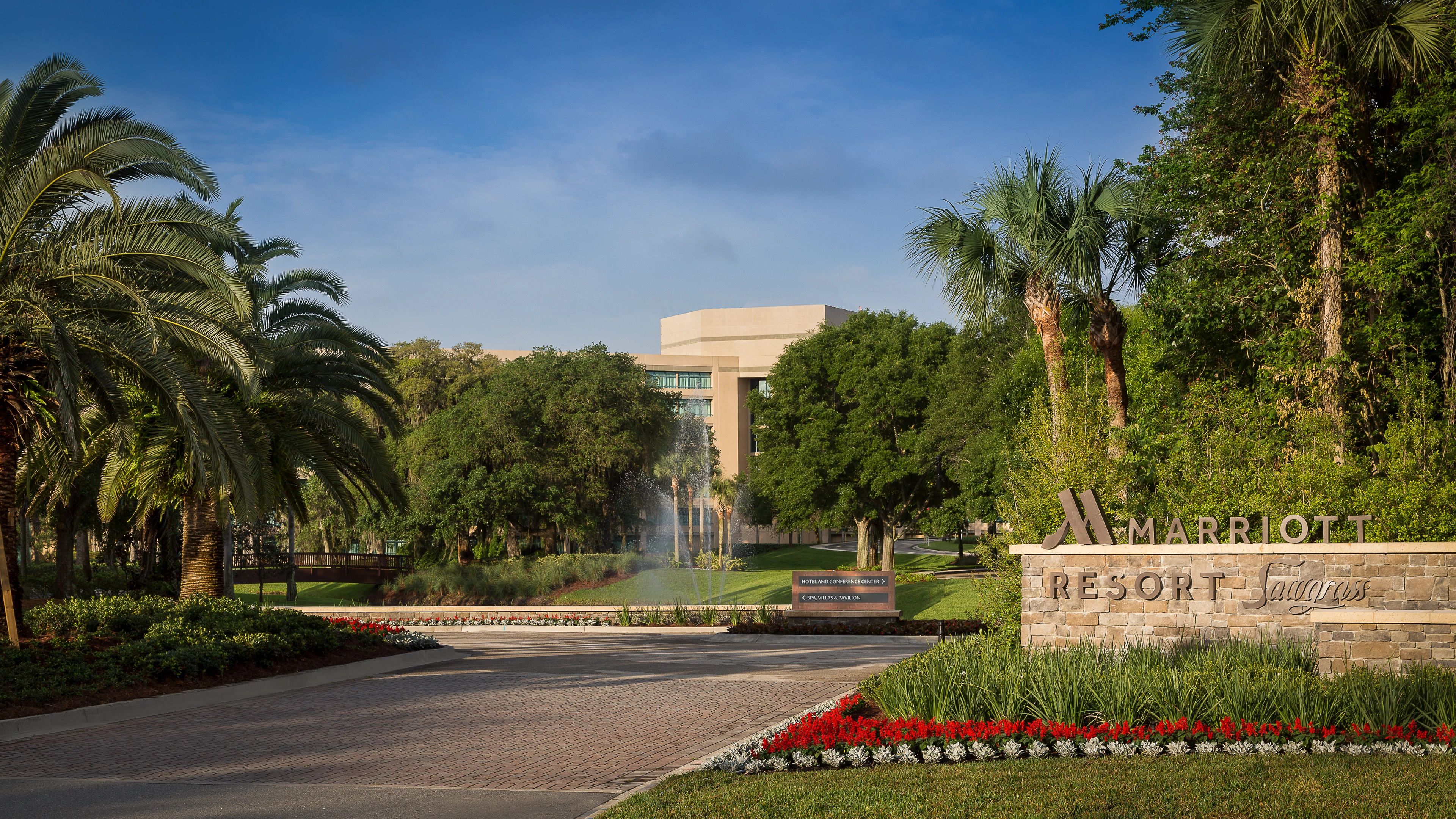 Entrance of the 5-star Marriott Sawgrass resort with palm trees, landscaped drive, and grand hotel facade at the main arrival area