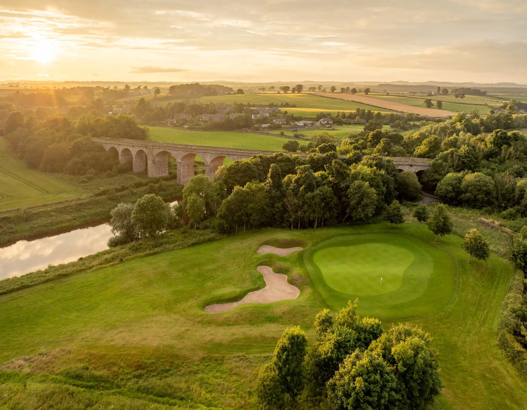 View over Roxburghe Golf Club course with manicured fairways, greens, and surrounding trees under a clear sky